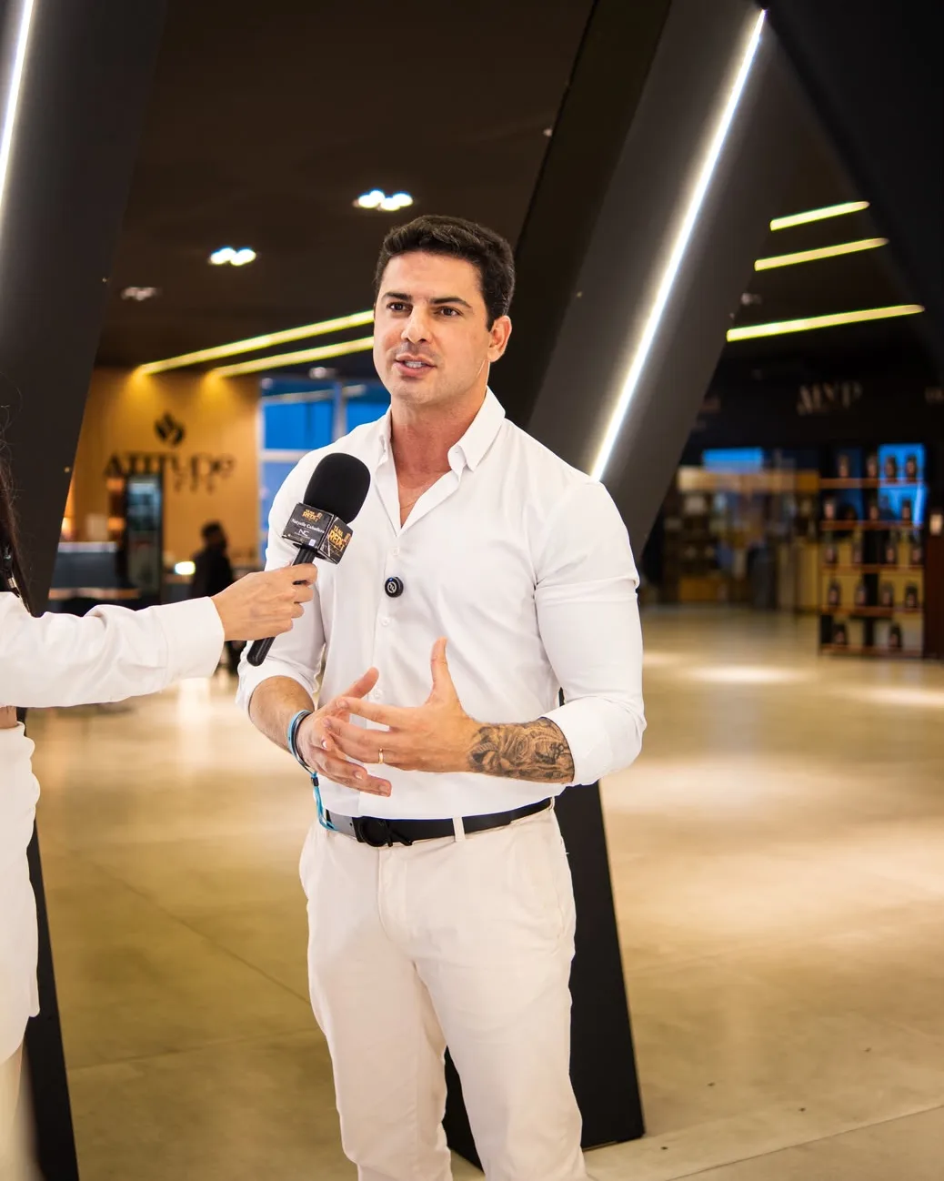 Bruno Inglez de camisa branca, dando entrevista com microfone em um evento