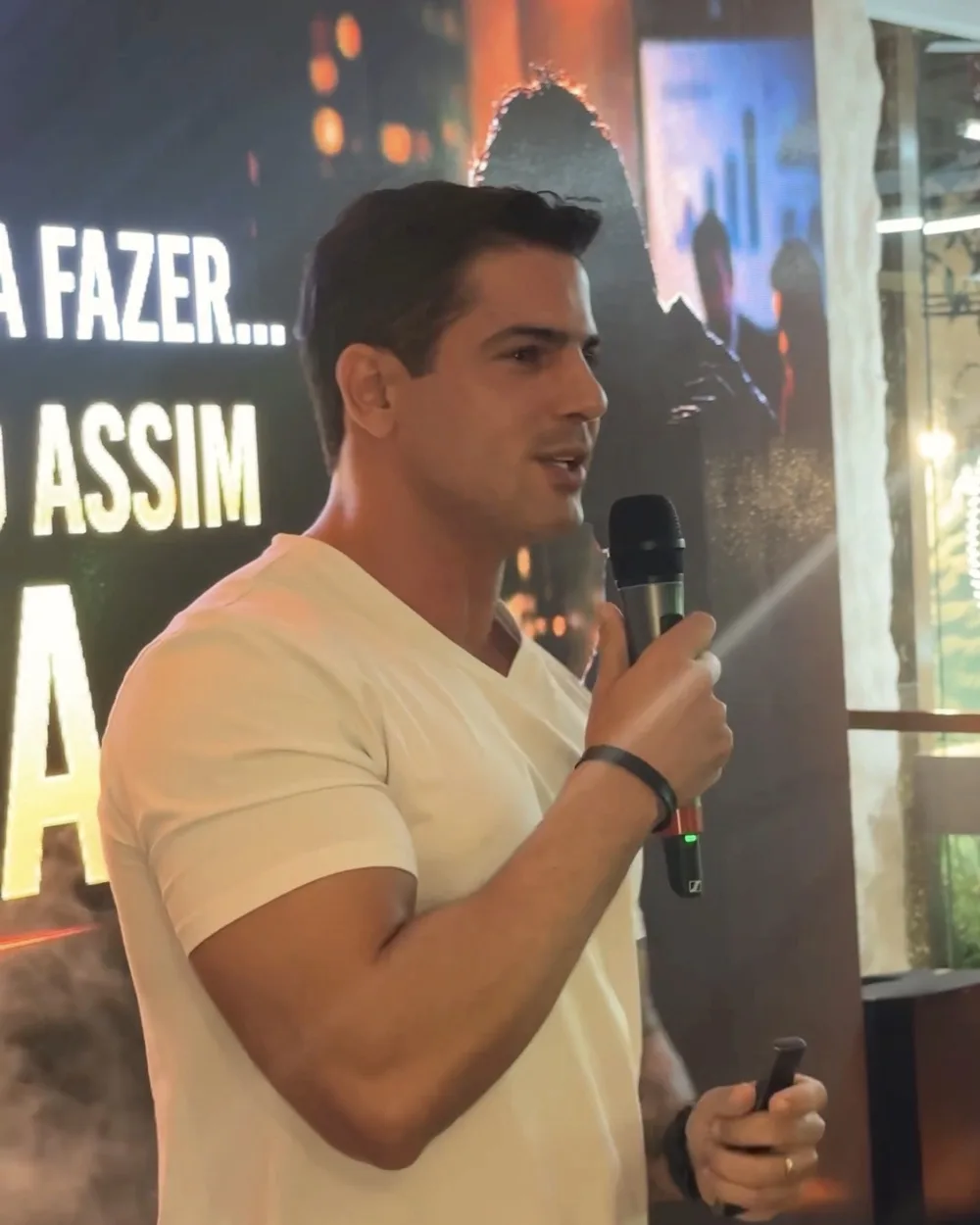 Bruno Inglez de camiseta branca, falando ao microfone em um evento